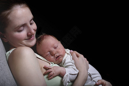 睡梦中的母亲胸部上有一个睡着的婴儿图片