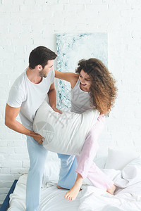 穿着睡衣快乐的年轻夫妇与枕图片
