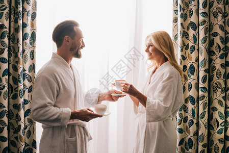 一边是快乐的中年夫妇在浴袍里喝咖啡图片
