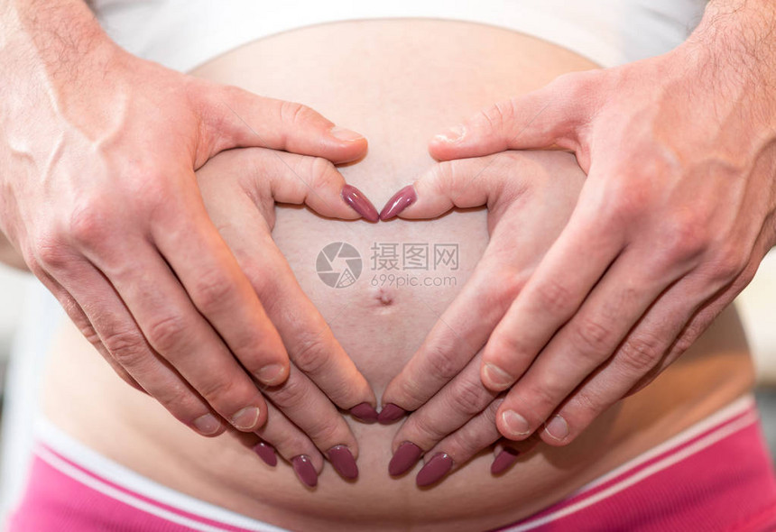 夫妻在怀孕肚子上握着双图片