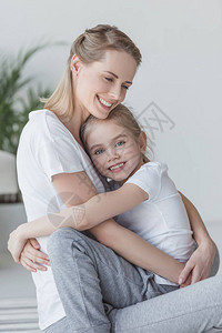 快乐美丽的母亲和女儿拥抱和看着摄影机图片
