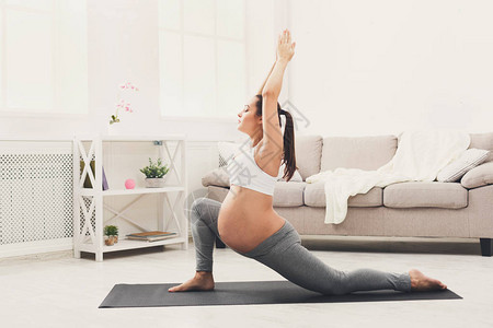快乐的孕妇以英雄姿势训练瑜伽母积极怀孕幸福训图片