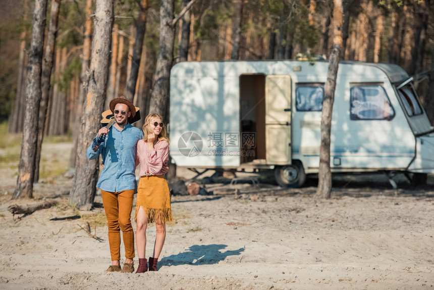 年轻嬉皮夫妇并站在森林露营地附图片