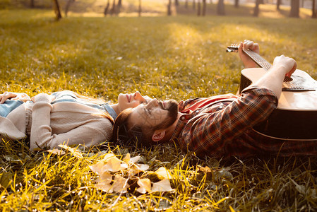 幸福的情侣躺在秋天公园的草地上而男图片
