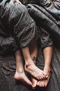 年轻夫妇的双腿在早上一起躺在床上图片