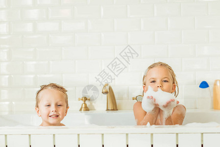 快乐的小孩坐在浴缸里带着泡沫图片