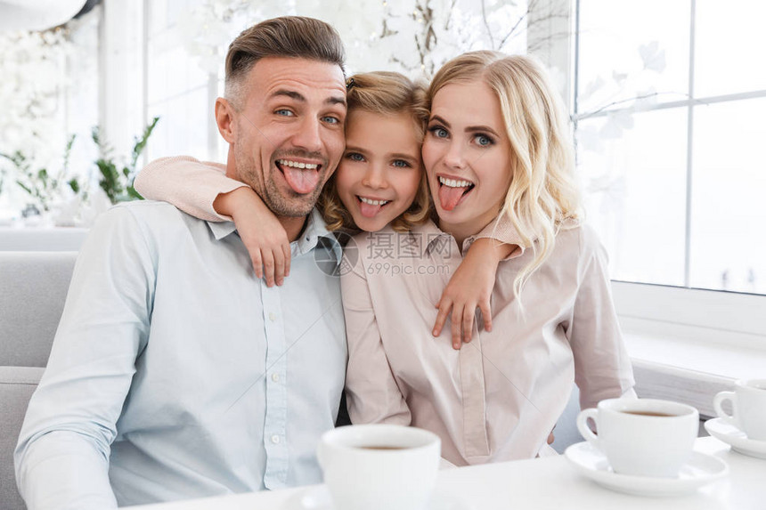 快乐的年轻家庭在咖啡馆里做恶作剧图片
