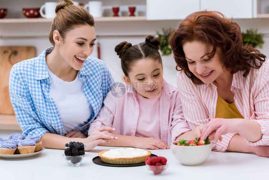 三代妇女一起在厨房装饰甜品和图片