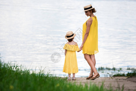 美丽的母亲和女儿在河边站着时图片