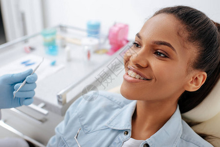 整牙医生把牙科器械放在非洲幸福病人的牙套上图片