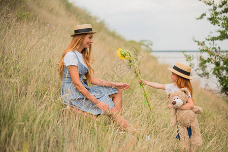 有泰迪熊的可爱小女孩向在草地上快乐的图片