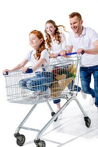 年轻快乐的父母带着可爱的红发女儿在购物车里被图片