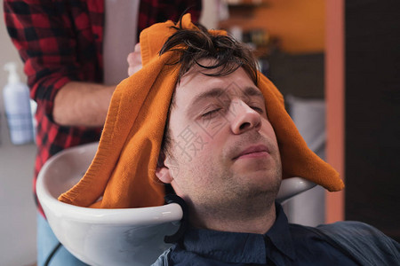 发型师正在洗客户头发麦加年轻男子理发时图片