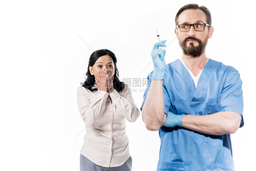 害怕的女病人用注射器看医生被白色隔离图片