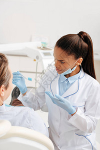 用乳胶手套亲手指着靠近病人牙刷的非洲美国牙医图片
