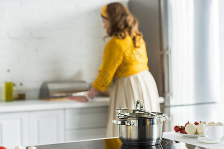 女人在厨房做饭前景是电炉上的平底锅图片