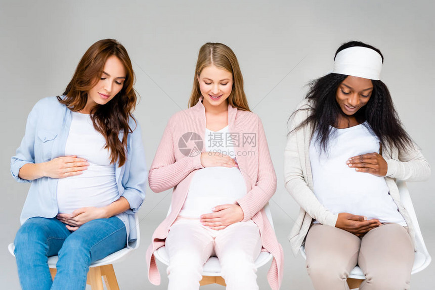 多种族孕妇触摸肚腹和在灰色图片