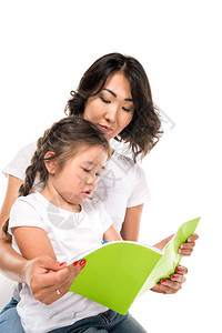 美丽的亚洲母亲和女儿写着一本书在图片