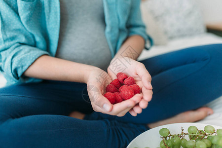 年轻孕妇在床上吃葡萄和草莓的青春图片
