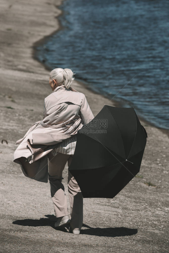 穿着黑色雨伞和在河边行走的外套上身穿大衣图片