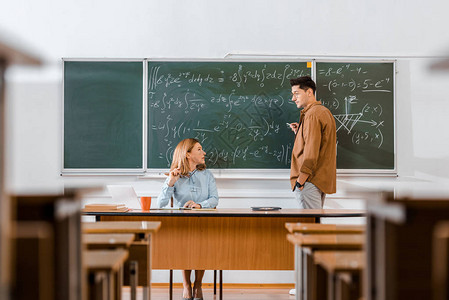 男学生在课堂上看着女老师并解方程背景图片