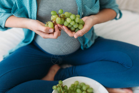 年轻孕妇在床上吃葡萄图片