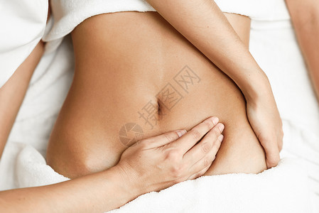 女腹部按摩手术师对腹部施压在温泉理发店接受图片