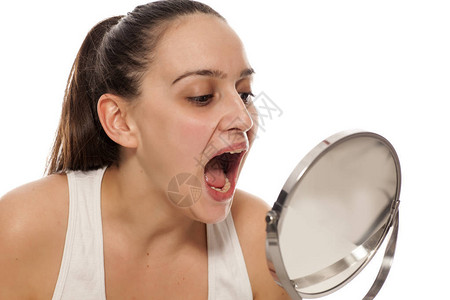 年轻女子在镜子里检查她的嘴图片