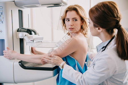 青年放射学家为病人在X光机上进行乳腺造图片