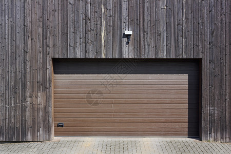 现代农村车库木墙与自动举的门入口上方墙上的运动传感图片