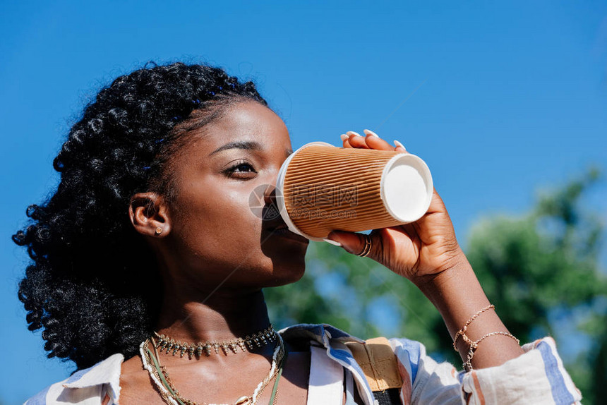 非裔美国妇女一边喝着咖啡的可支配杯子图片