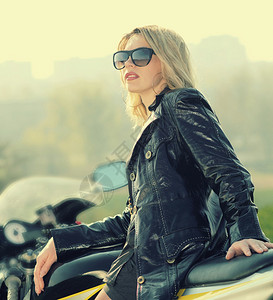 一个美丽的金发女人的肖像戴着墨镜坐在运动摩托车上图片