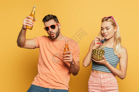 兴奋的男子与啤酒瓶靠近金发女孩喝鸡尾酒从菠萝鸡图片