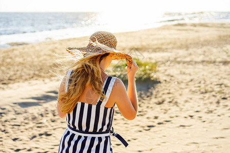 戴草帽的女人走在沙滩上的背影图片