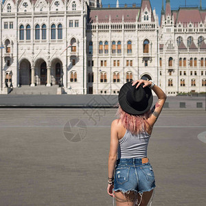 年轻戴帽子的女青年看国会大楼在最茂盛图片