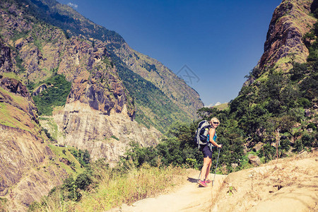 在尼泊尔喜马拉雅山背着包登山的女背包客在高山徒步旅行和徒步旅行安纳普尔纳环线跋涉中的安纳普尔纳喜马尔山脉亚洲背景图片