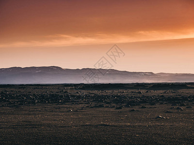 日落时黑沙岩石和山丘图片
