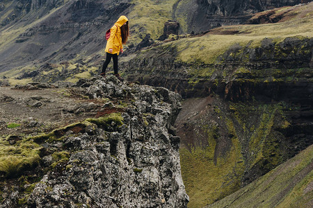从冰岛山的悬崖上往下看的年轻女人图片