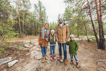 寒秋日年轻美丽的家庭站在森林道路图片