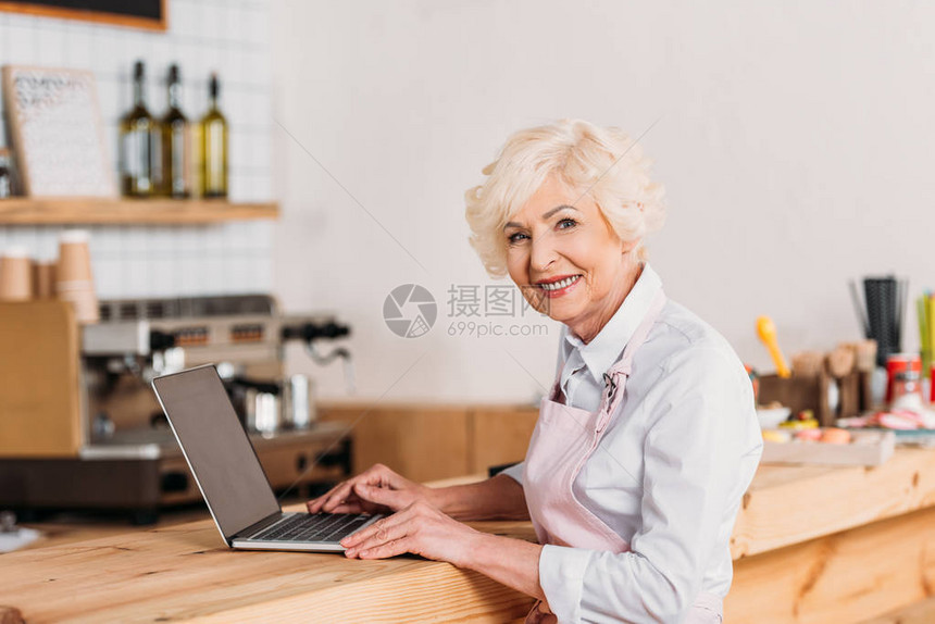 在咖啡厅柜台用笔记本电脑微笑的高级咖啡图片
