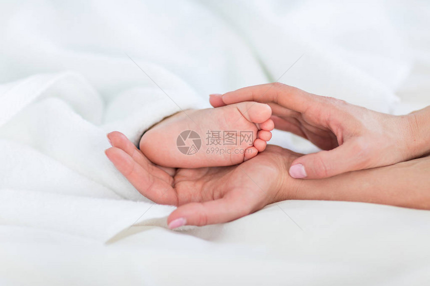 近距离观察一岁婴儿1岁躺在毯子下抱着脚的婴儿的母图片