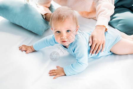 婴儿在床上爬行时母亲抱着她图片