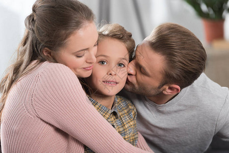 有两个父母拥抱和亲吻小儿子时他正图片