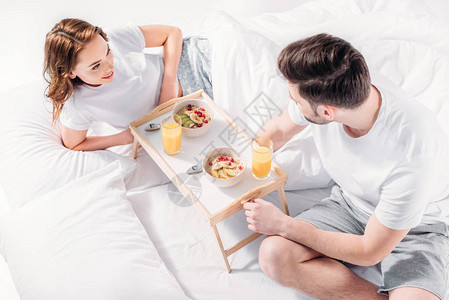 年轻夫妇早上一起在床上吃早餐的高度图片