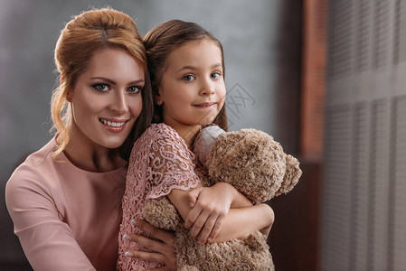 母亲抱着泰迪熊时拥抱女儿而她图片