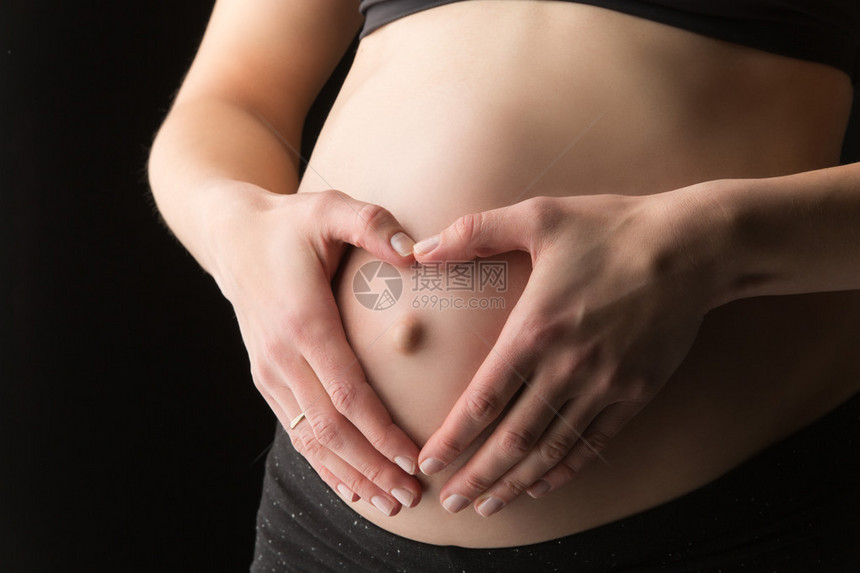 孕妇腹部手牵心形的特写图片