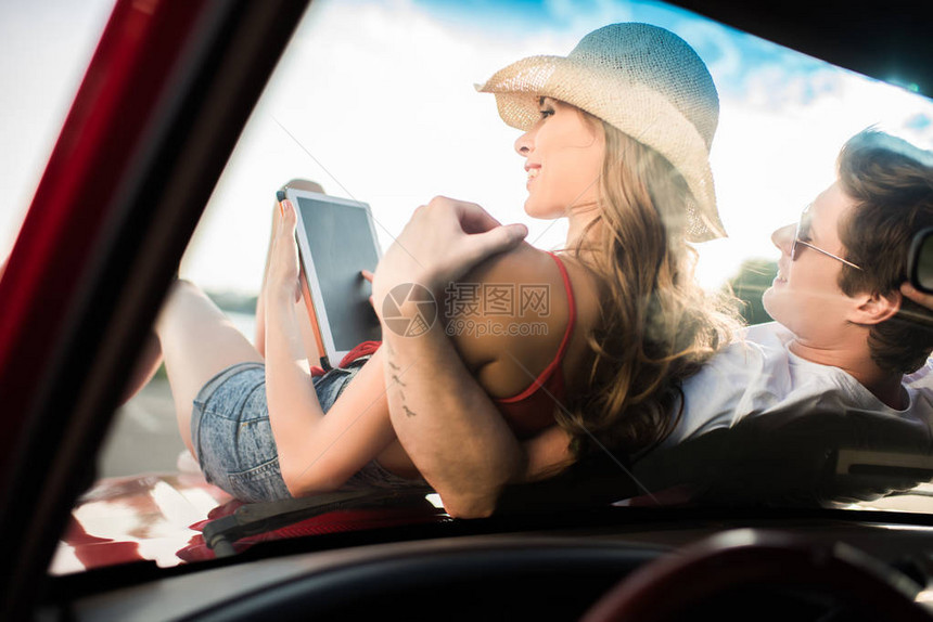 年轻男子在坐车上时用数字平板电脑拥图片