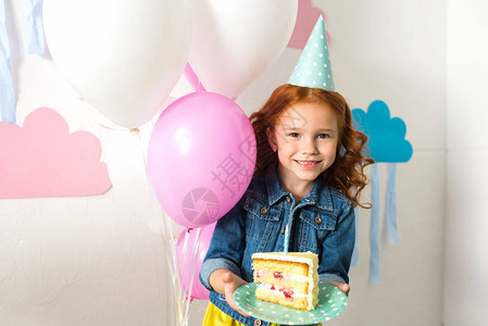穿着派对帽子的可爱红发美女拿着生日蛋糕图片