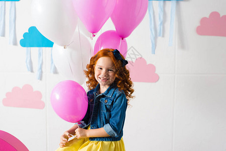 可爱的红发女孩肖像拿着粉红色气球在生日派对上图片