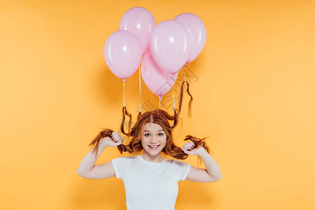 快乐的红发女孩带着气球绑在头发上的气球在图片